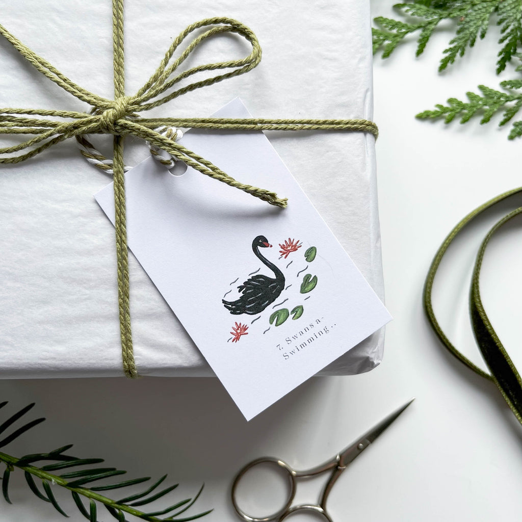 12 days of christmas hand illustrated 7 swans a swimming gift tag on box with string & winter foliage 