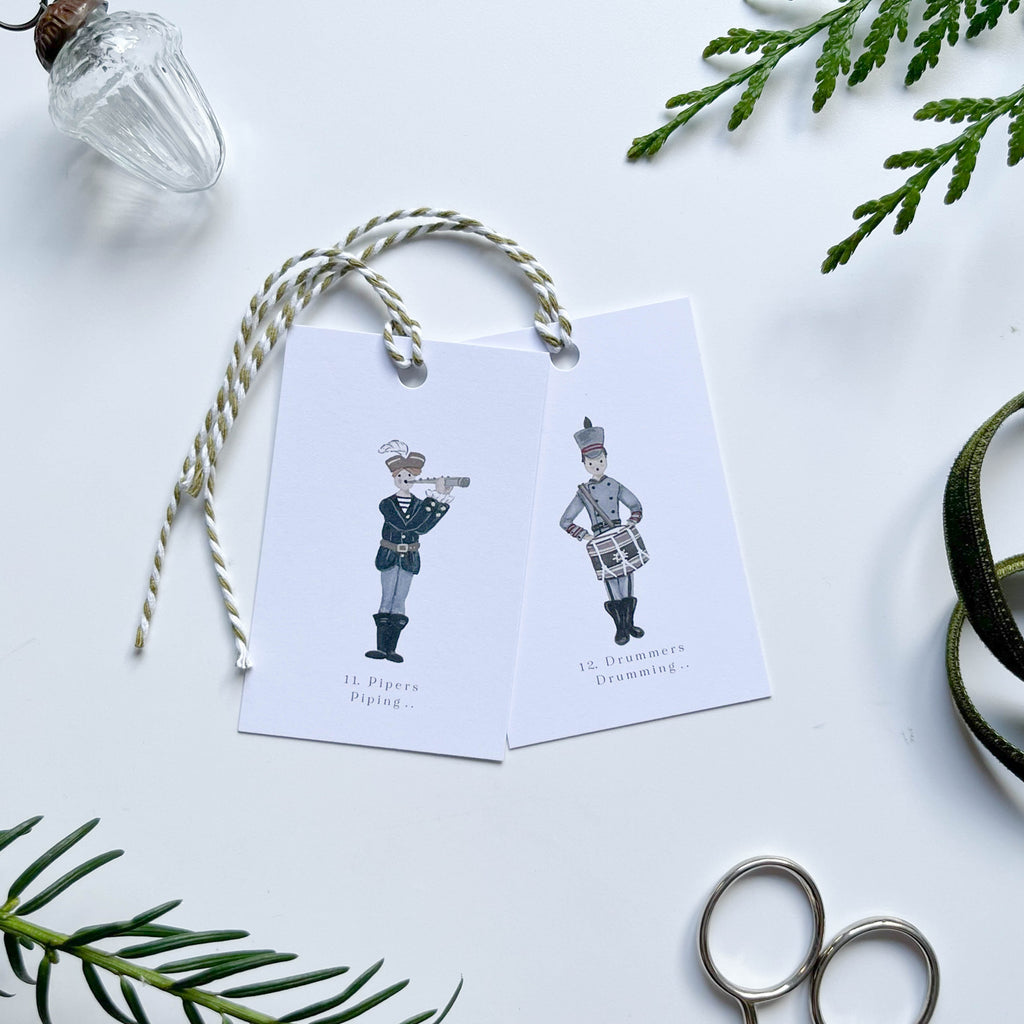 pipers piping drummers drumming hand illustrated 12 days of christmas gift tags with stripey bakers twine bauble & winter foliage